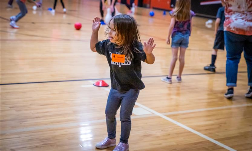 A girl wearing a black shirt teases a classmate during a game of dodgeball